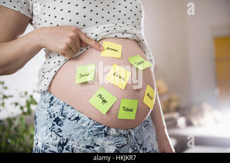 Femme enceinte avec des noms de bébé sur le ventre, Munich, Bavière, Allemagne Banque D'Images