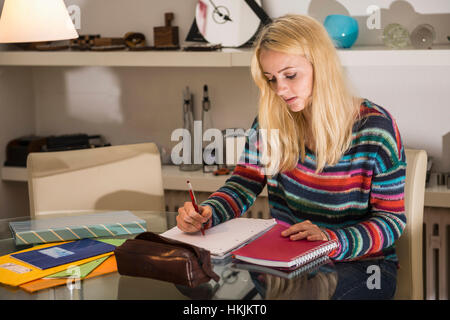 Jeune étudiant à faire leurs devoirs dans le salon, Bavière, Allemagne Banque D'Images