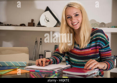 Portrait d'un jeune étudiant à faire leurs devoirs dans le salon, Bavière, Allemagne Banque D'Images