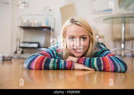 Portrait d'une belle jeune femme couchée sur le plancher dans le salon, Bavière, Allemagne Banque D'Images