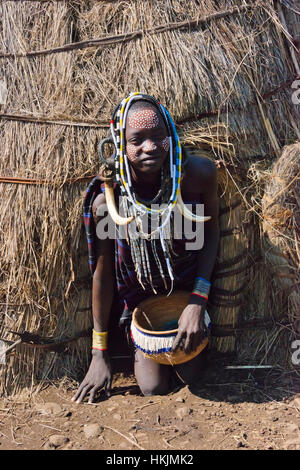 Les gens de la tribu Mursi en costume traditionnel en face de la maison de paille traditionnel, Mursi, village du sud Omo, Ethiopie Banque D'Images