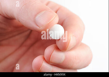 Comprimé rond blanc de macro dans la main on white Banque D'Images