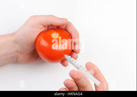 Coup de tomate avec seringue sur fond blanc Banque D'Images