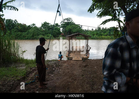 Les hommes qui contrôlent un radeau en bois ont servi de traversier pour traverser la rivière à Pakis Jaya, Karawang, West Java, Indonésie. Banque D'Images