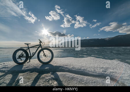 Fatbike aussi appelé vélo fat ou fat-vélo pneus vélo - sur roues pneu large. Cycliste va à son vélo sur le lac gelé. Photo prise dans le mode HDR. Banque D'Images