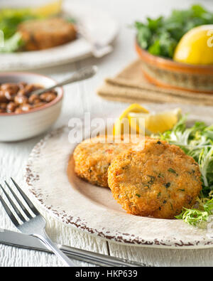 Délicieuses galettes de poisson pané avec des haricots blancs. Banque D'Images