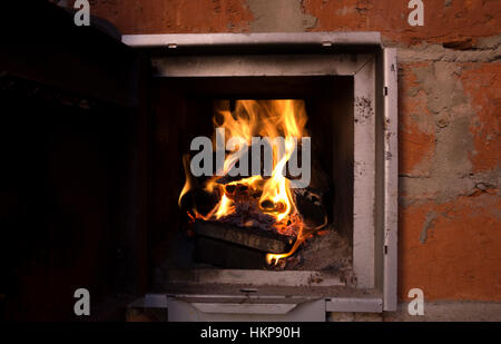 Incendie dans un foyer de la porte ouverte de la paroi en briques orange close up focus sélectif copy space Banque D'Images