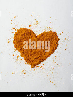 Rez-de curcuma ou curry en poudre formé en forme de cœur sur une surface blanche Banque D'Images