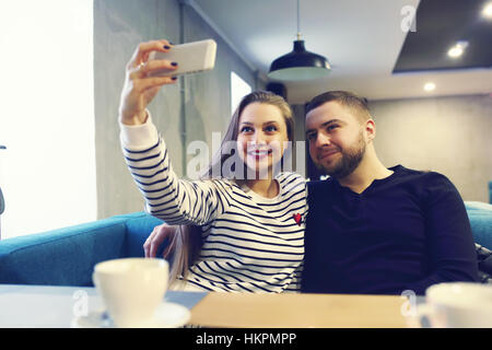 Happy young couple with smartphone en tenant à selfies cafe dans centre commercial. vente, shopping, le consumérisme, la technologie et les gens concept - Banque D'Images