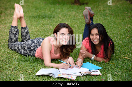 Les filles avec l'apprentissage sourire étendu sur l'herbe verte Banque D'Images