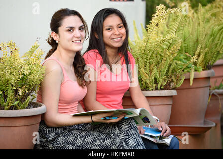 Smiling pretty girls latino avec les ordinateurs portables s'asseoir dans le parc Banque D'Images