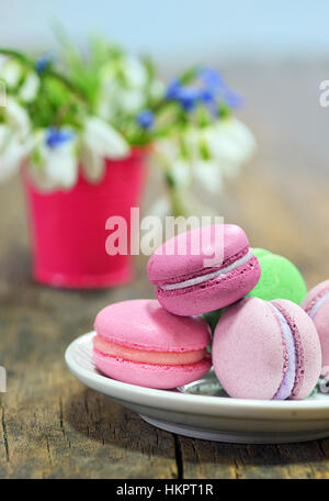 Macarons colorés et fleurs de printemps sur table en bois Banque D'Images