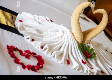 Les oiseaux de décoration avec des pétales de rose rouge sur blanc nettoyer lit dans chambre d'hôtel Banque D'Images