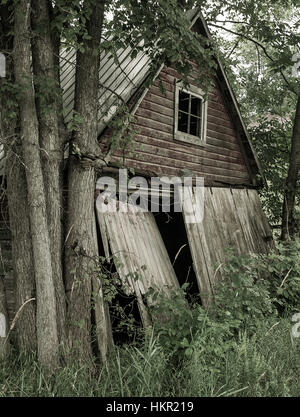 Un vieux bâtiment, depuis longtemps abandonné et envahi par les feuilles et les branches se trouve le long du côté d'une route dans la région de Muskoka Ontario Canada. Pi Banque D'Images