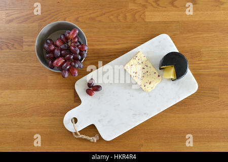 Plateau de fromage en marbre blanc dans une cuisine avec du fromage et du raisin Banque D'Images