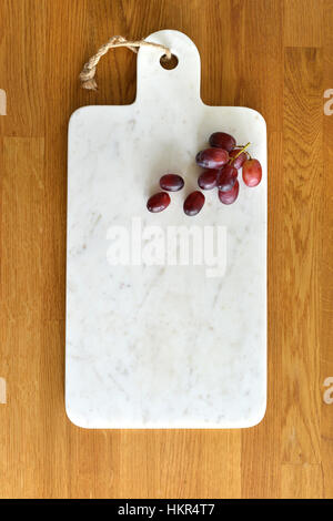 Plateau de fromage en marbre blanc dans une cuisine avec du fromage et du raisin Banque D'Images