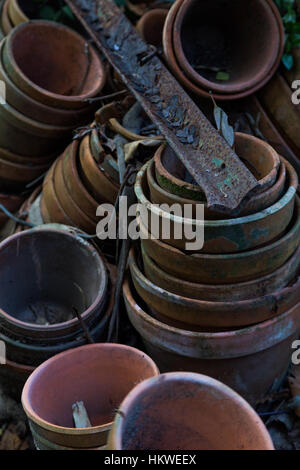 Sale vieux pots de fleurs empilées dans un jardin Banque D'Images