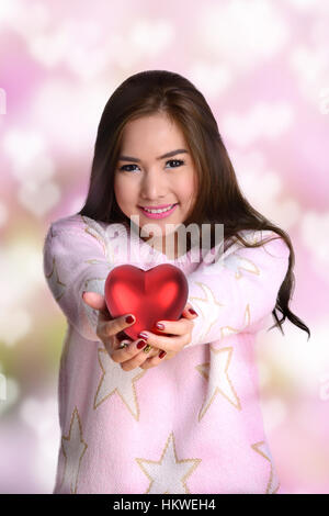 Smiley girl holding big red heart en deux mains donner à quelqu'un. Banque D'Images