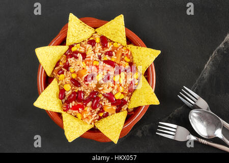 Chili con carne végétarien dans un bol avec des croustilles sur fond ardoise, vue du dessus. Banque D'Images