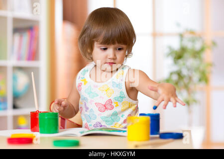 Cute child girl painting ses doigts dans des couleurs vives Banque D'Images