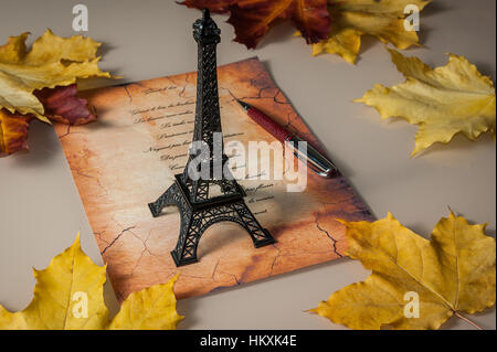 Statuette de Tour Eiffel, feuilles jaunes, le verset en français, une vieille lettre Banque D'Images