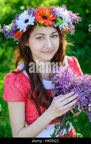 Belle jeune femme avec une couronne sur sa tête et le bouquet de lilas Banque D'Images