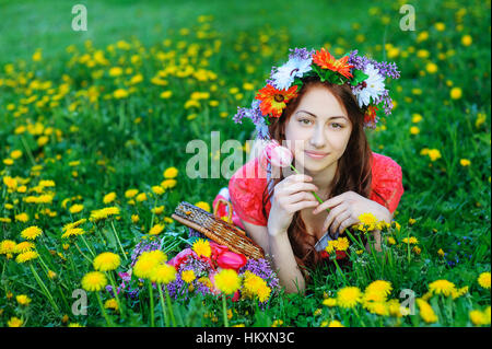Jeune femme en robe rouge couché sur l'herbe dans le pré Banque D'Images