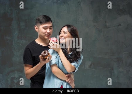 Jeune couple asiatique aiment manger des patates donut coloré Banque D'Images