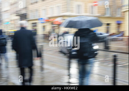 Les gens marchent dans la rue sous la pluie. l'accent floue Banque D'Images