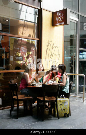 Les jeunes sont assis à une table devant le café Max Brenner, étudier le menu, Melbourne, Victoria, Australie Banque D'Images