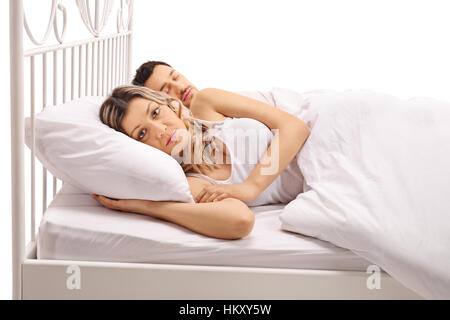 Worried woman Lying in Bed avec un mec dort à côté d'elle isolé sur fond blanc Banque D'Images