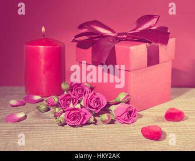 Boîte cadeau rouge attaché avec ruban décoratif, bouquet de fleurs, roses et bougie coeurs jouet en bois sur fond de table, Valentines Day concept, Close up, à Banque D'Images