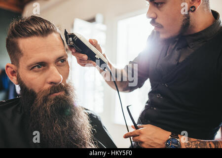 Jeune homme se coupe au salon de coiffure. La coupe de cheveux coiffeur de client dans un salon de coiffure. Banque D'Images