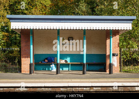 Gare de Leominster, Herefordshire, Royaume-Uni. Un passager dormant sur un banc en attendant un train très retardé Banque D'Images