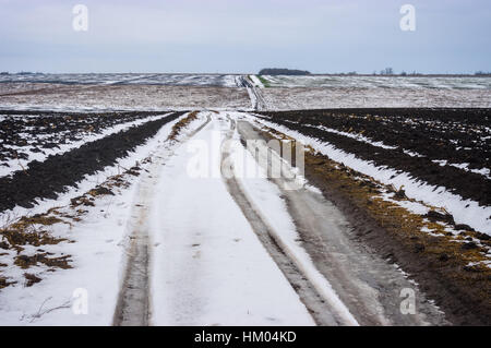 Paysage vallonné avec des routes de campagne entre les champs agricoles au centre de l'Ukraine à la fin sombre journée d'automne Banque D'Images