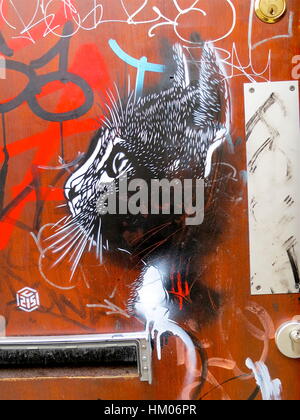 Street Art Par C215, Christian Guemy. Pochoir chat sur une porte rouge à Shoreditch, London. Banque D'Images