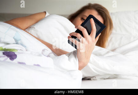 Femme au lit avec smarthphone Banque D'Images