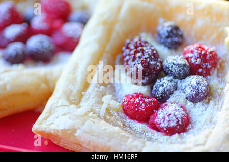 Les framboises, les bleuets et les mûres sur la pâte feuilletée avec du sucre en poudre Banque D'Images