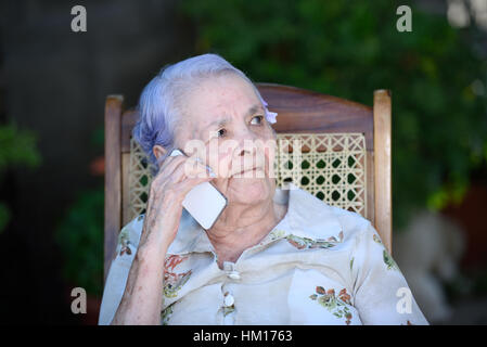Vieille grand-mère parler sur smartphone blanc moderne. Banque D'Images
