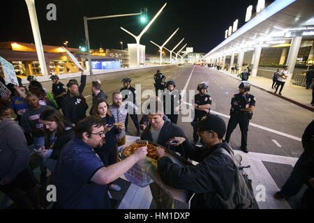 Los Angeles, USA. 29 janvier, 2017. Prendre une pause pizza manifestants, tout en bloquant le trafic pendant une manifestation au niveau des départs en face du Terminal International Tom Bradley (TBIT) à l'Aéroport International de Los Angeles (LAX) suite à l'atout de Donald's interdiction de voyager à partir de pays à majorité musulmane à Los Angeles, Californie. Les protestataires arrêtez l'abaisser et zone des arrivées. Crédit : Patrick Fallon/ZUMA/Alamy Fil Live News Banque D'Images