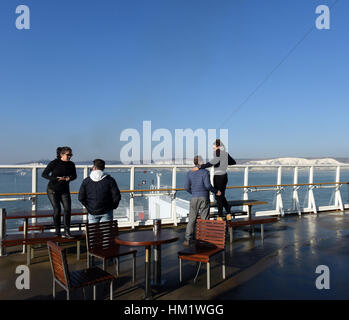 Les passagers sur un pont découvert à bord de P & O Ferries bateau laissant Dover Harbour port avec des falaises blanches Banque D'Images