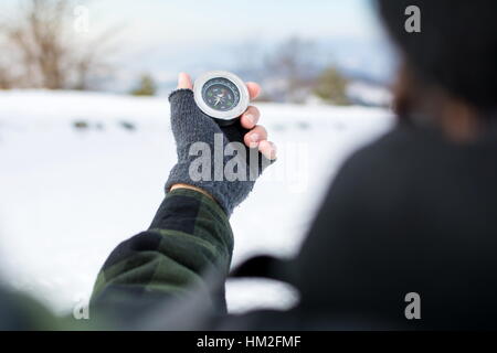 Homme tenant un compas métal on snowy mountain Banque D'Images