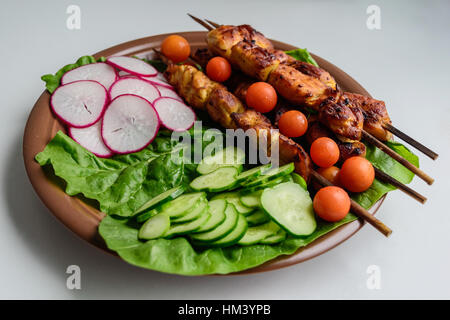 Brochette de poulet avec des légumes sur une plaque d'argile Banque D'Images