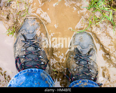 Une paire de bottes de marche sur un chemin boueux. Banque D'Images