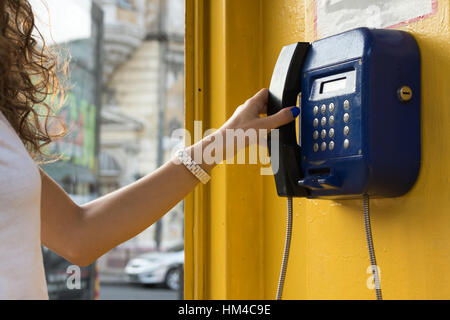 La main féminine contient jusqu'au téléphone. Appel à partir de téléphones publics de la ville. Banque D'Images