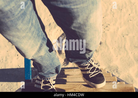 Les jambes des hommes en jeans et baskets qui monte les escaliers. Vue supérieure, close-up, tonique de l'image. Banque D'Images