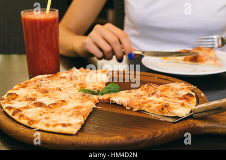 Mangé une pizza et un verre de jus de tomate sur la table à la pizzeria. Femme en train de déjeuner dans le café. Banque D'Images