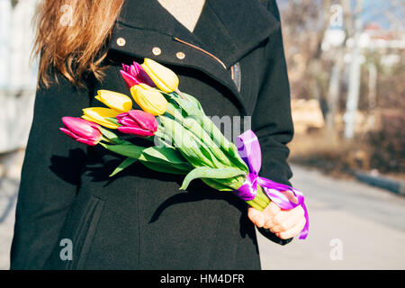 Femme en manteau noir tenant un superbe bouquet de fleurs, un jour ensoleillé Banque D'Images