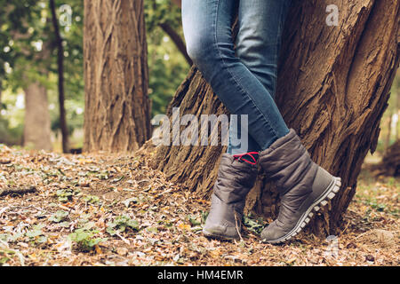 Close-up de femmes jambes en jeans et bottes in autumn park Banque D'Images