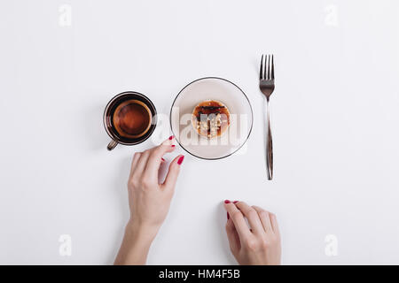 La main féminine avec manucure rouge prend le gâteau de la table, vue du dessus Banque D'Images